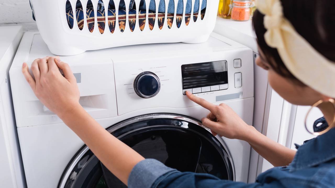 Blurred housewife switching washing machine in kitchen